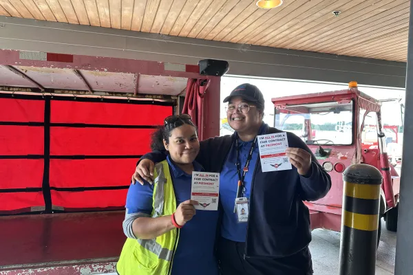 Two CWA Piedmont members stand with signs of support.